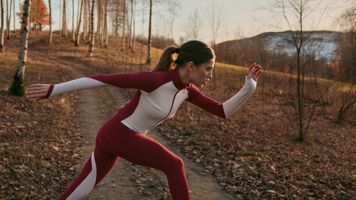 Woman doing skater bounds on an autumn trail as part of a dryland ski training program before opening day